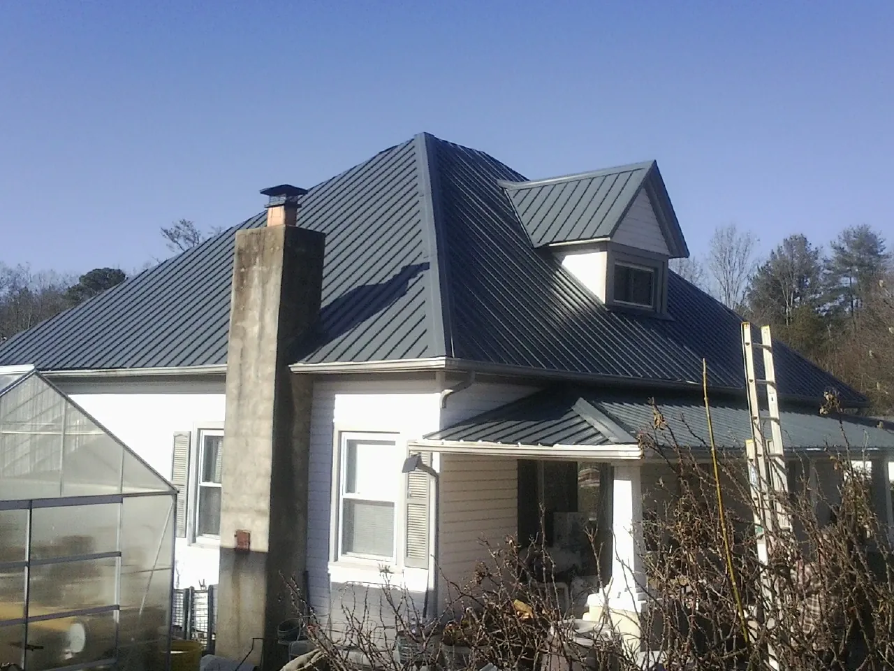 Dark blue standing seam metal roof on a white farmhouse with dormer — Slate & Tile Roof Repair by Roofing Brothers in Womelsdorf