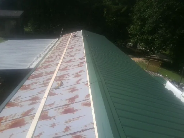 Old rusted panels beside newly installed green metal roofing — Wind Damage Roof Repair by Roofing Brothers in Womelsdorf