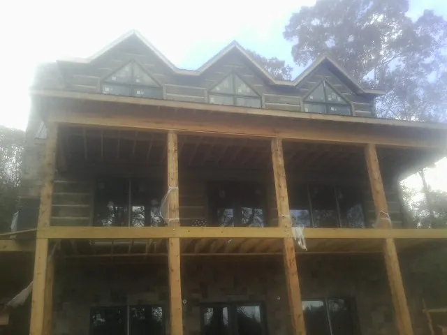 Dormers and porch framing on a large log home under construction — Roof Coating work by our crew in Womelsdorf