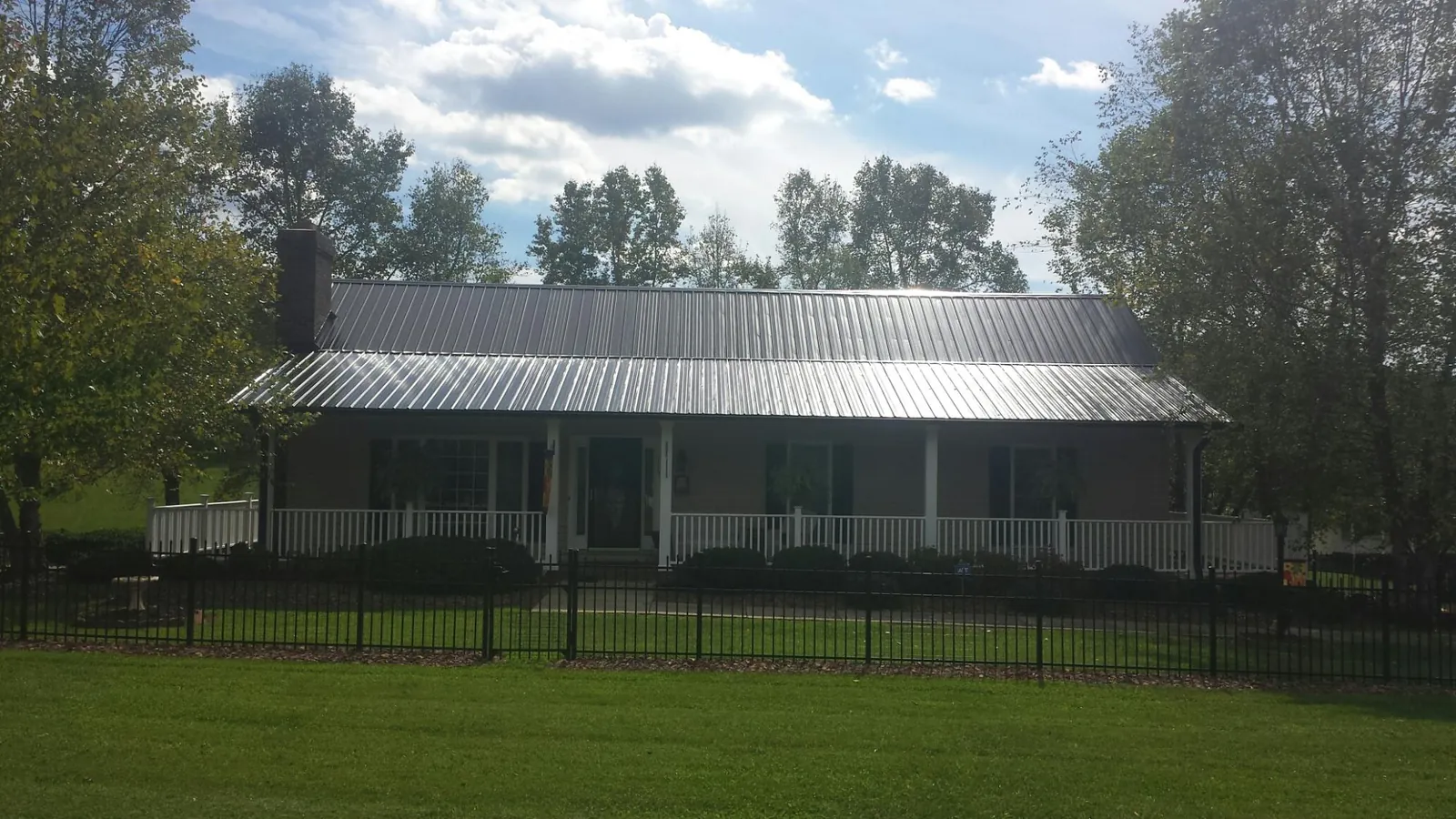 Gray metal roof on a brick ranch with a full width front porch — Gutter Guard Installation work by our crew in Womelsdorf