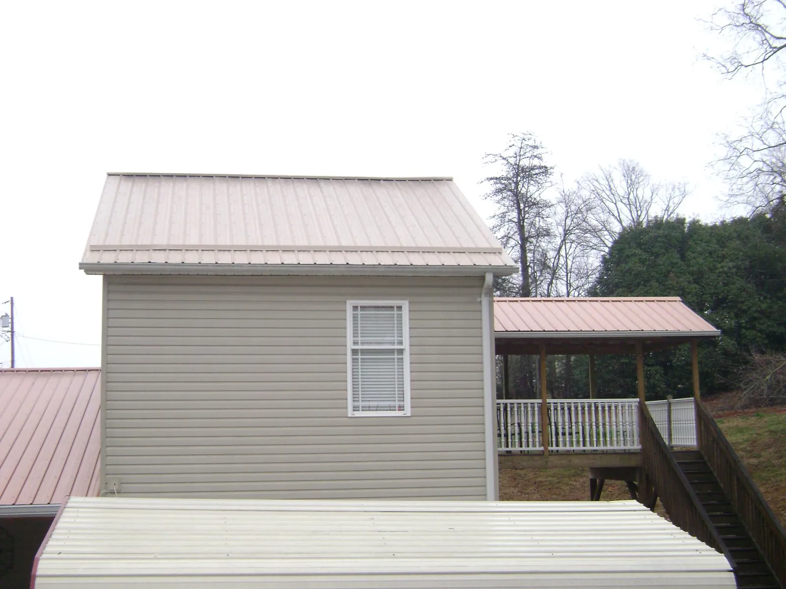 Tan metal roofs on a two story addition and attached porch, from a Roof Replacement job in Womelsdorf